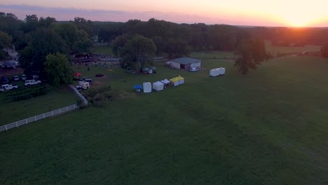 Vuele-Sobre-Un-Dron-De-4k-Que-Empuja-Lentamente-El-Festival-De-Música-Y-Arte-Rural-En-Una-Granja-Histórica-Al-Atardecer