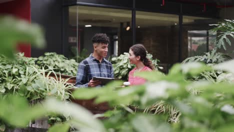 Two-happy-diverse-creative-designers-in-discussion-at-tablet-in-casual-office,-slow-motion