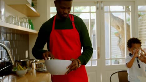 vista frontal de un joven padre negro lavando verduras en la cocina de una casa cómoda 4k