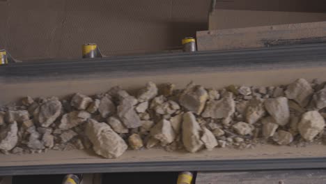 dusty crushed rock fragments on quarry conveyor bent in factory, czechia