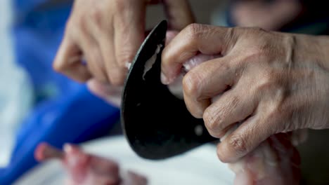 un cortador de verduras tradicional, conocido como "aruvamanai", se emplea para cortar carne de pollo cruda, mostrando la esencia de la preparación de comidas y la experiencia culinaria en la cocina
