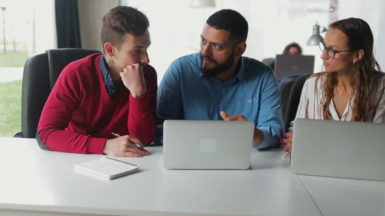 jóvenes trabajando con computadoras portátiles en la oficina.