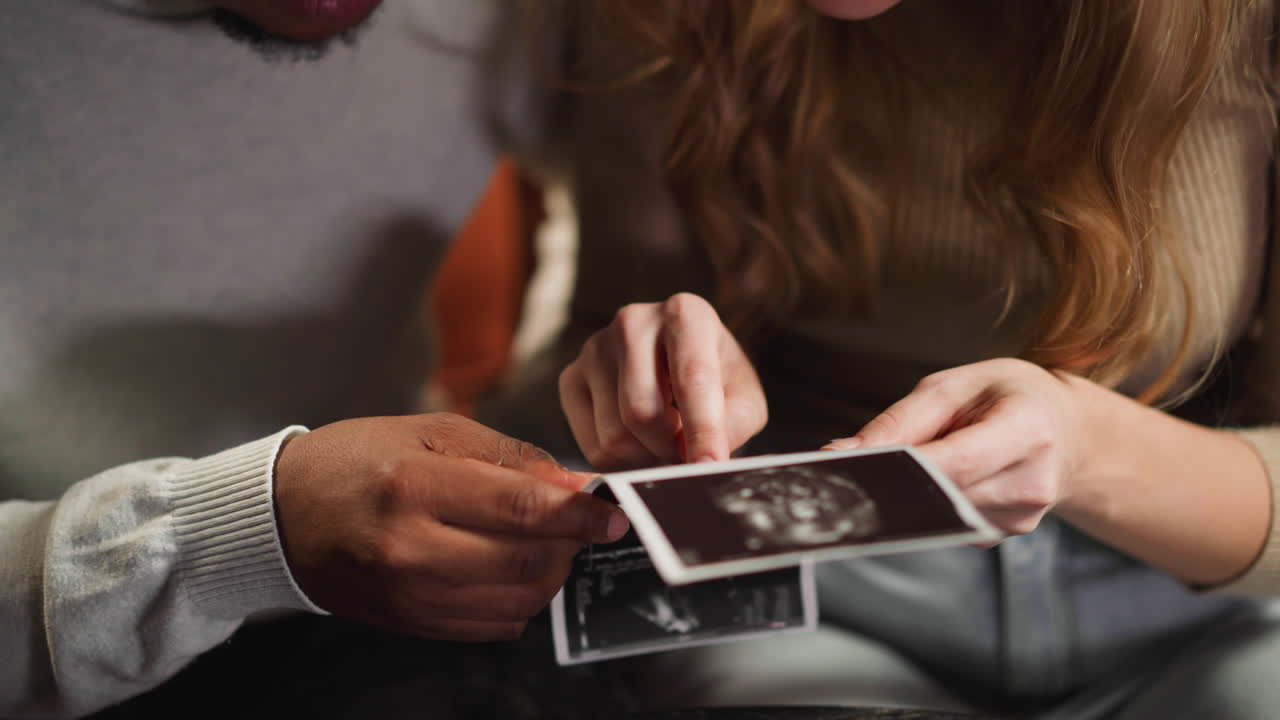 White woman shows baby on ultrasound pictures to husband
