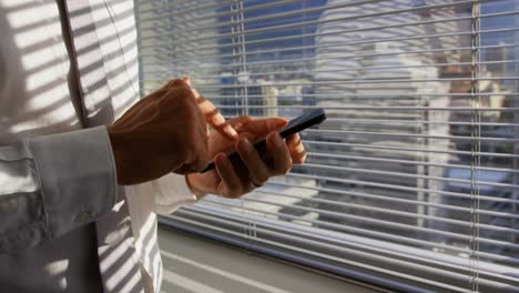 sección media de un joven ejecutivo caucásico usando teléfono móvil cerca de la ventana en una oficina moderna 4k