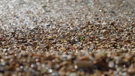 close up of waves splashing against pebbles on the beach