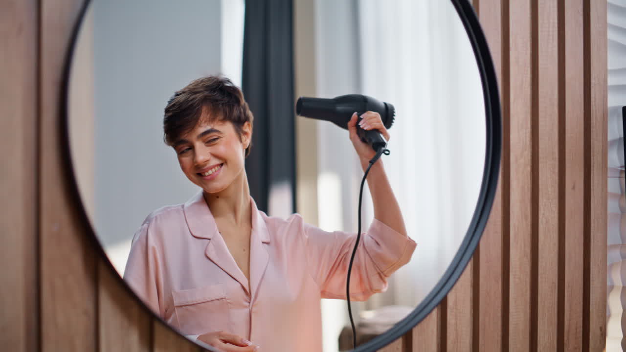 Excited housewife drying hair looking mirror closeup. Lady using hair dryer
