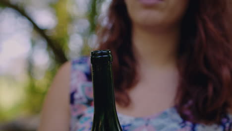 girl removes cork from wine bottle close shot