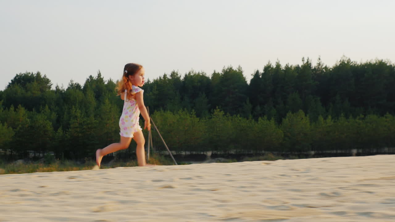 행복하고 명랑한 소녀는 숲 배경의 그림 같은 위치에서 모래 위를 달리는 것을 즐긴다