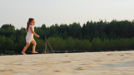 happy cheerful girl have fun running on the sand in a picturesque location on the forest background