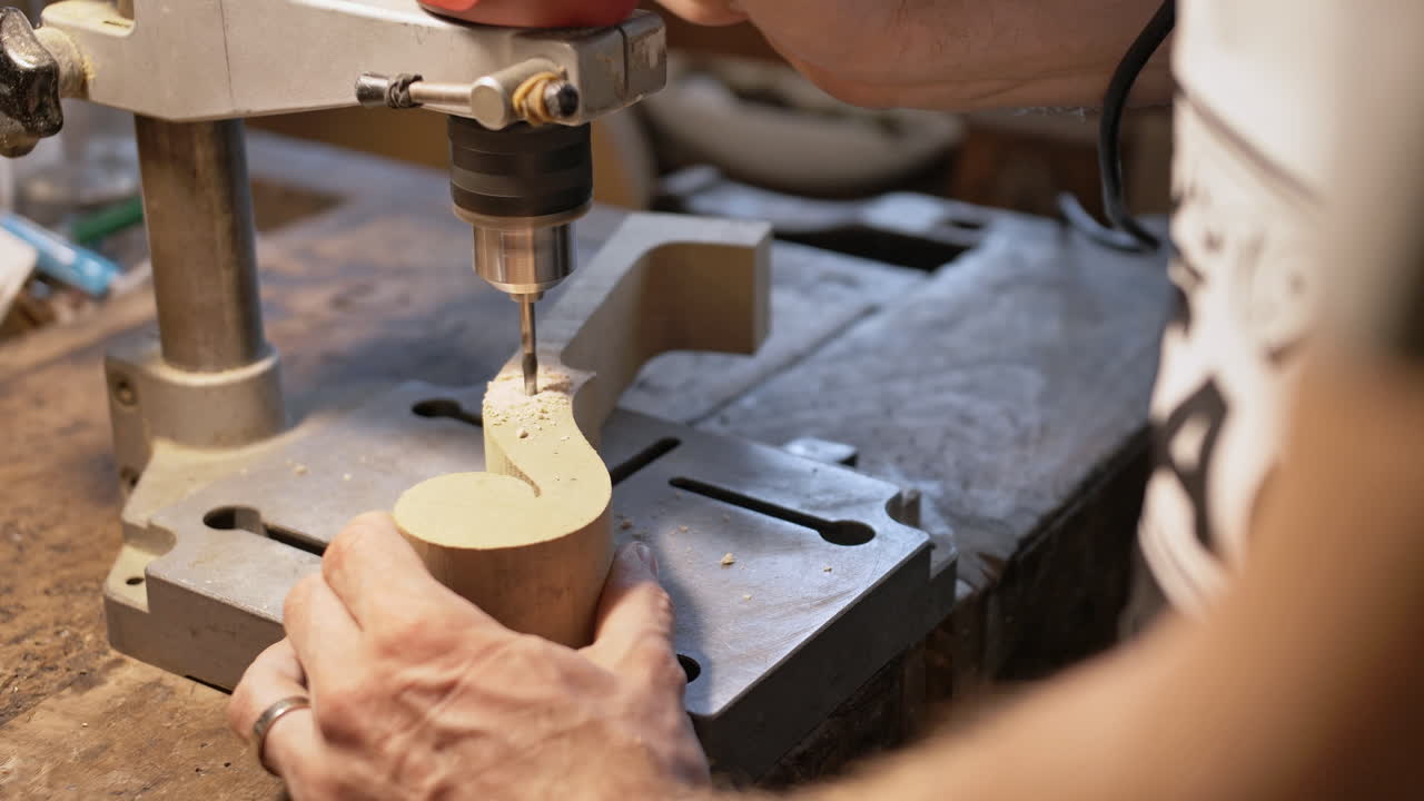 A violin maker prepares the top of a violin by drilling