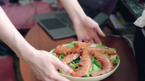 측면에 노트북이 있는 나무 테이블에서 제공되는 해산물 샐러드