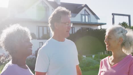 portrait of happy senior diverse people talking in garden on sunny day at retirement home