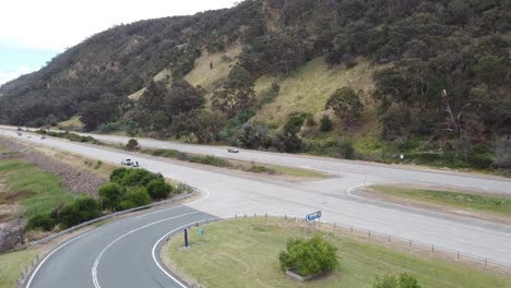 Vista-Aérea-De-Una-Intersección-Entre-Una-Autopista-De-4-Carriles-Y-Una-Zona-De-Descanso-Cerca-De-Un-Lago.