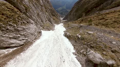 fotografiado deslizándose sobre un río congelado que serpentea a través de montañas áridas y rocosas, capturando el marcado contraste entre el río helado y el paisaje escarpado y estéril de canadá.