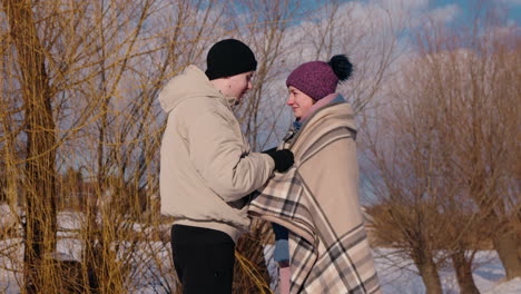 couple wrapped in blanket in snowy landscape