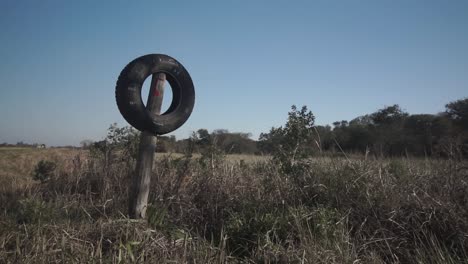 static shot of tire placed on wooden pole as entrance sign to farm, argentina