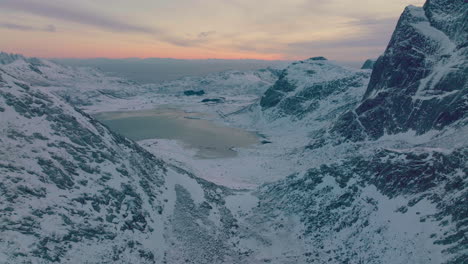 Ramberg-glacial-lake-fjord-aerial-view-pull-back-over-snowy-rocky-mountain-peaks-at-sunrise