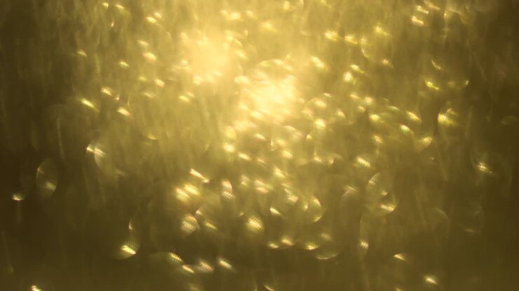 Glitter dorato, sfondo bokeh astratto, elegante polvere natalizia. Particelle brillanti e scintillanti. Movimento luminoso scintillante
