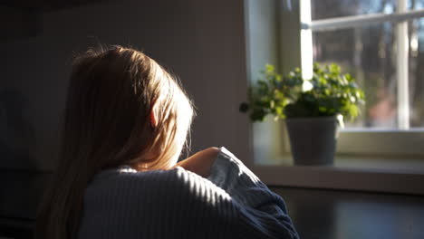 Girl-indoors-in-front-of-a-window-with-sun-light-shining-through