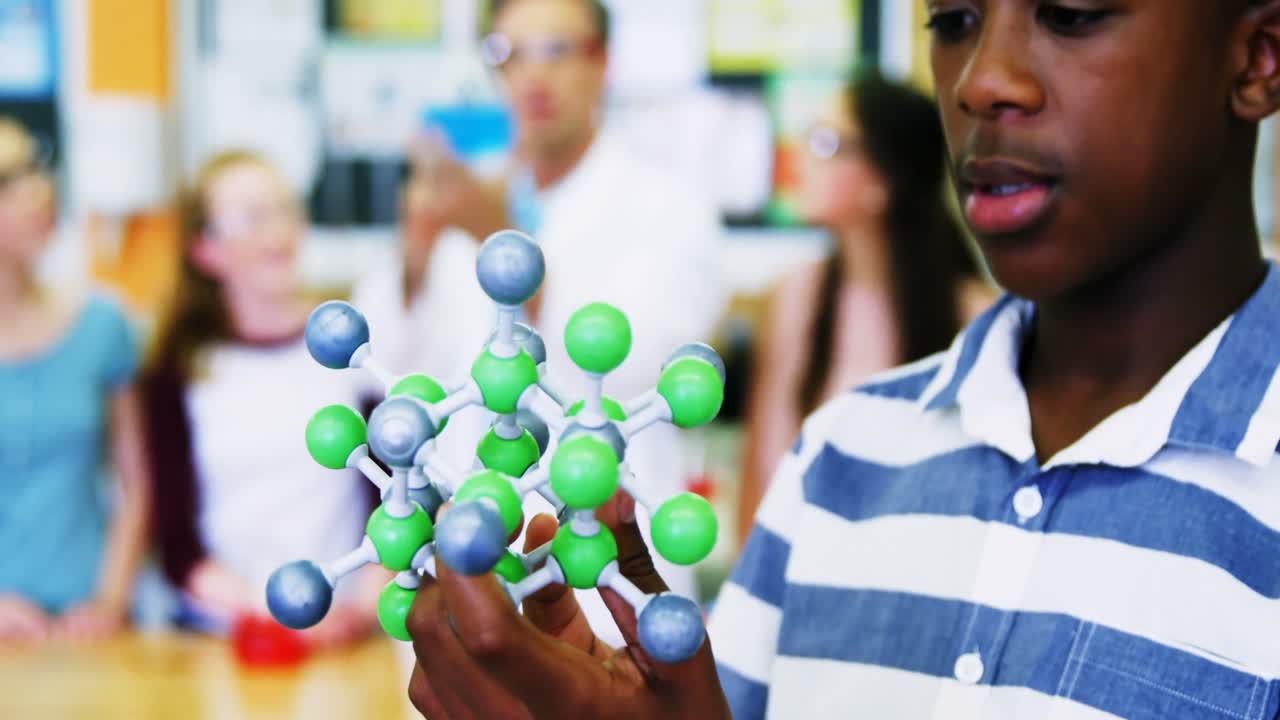 Close-up of schoolboy examining molecule model 4k