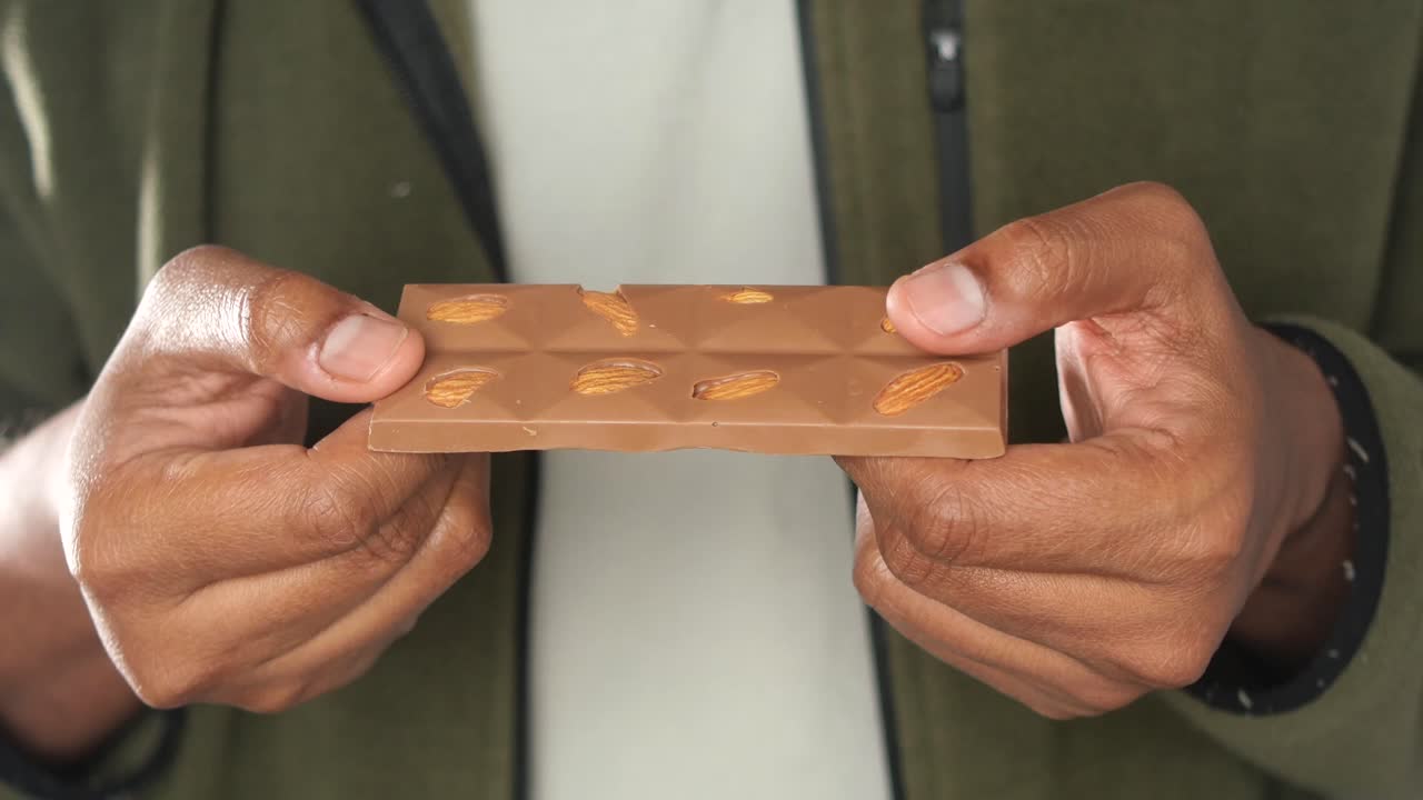 Chocolate bar with almonds held in hands