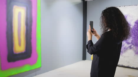 woman taking a photo of abstract art in an art gallery