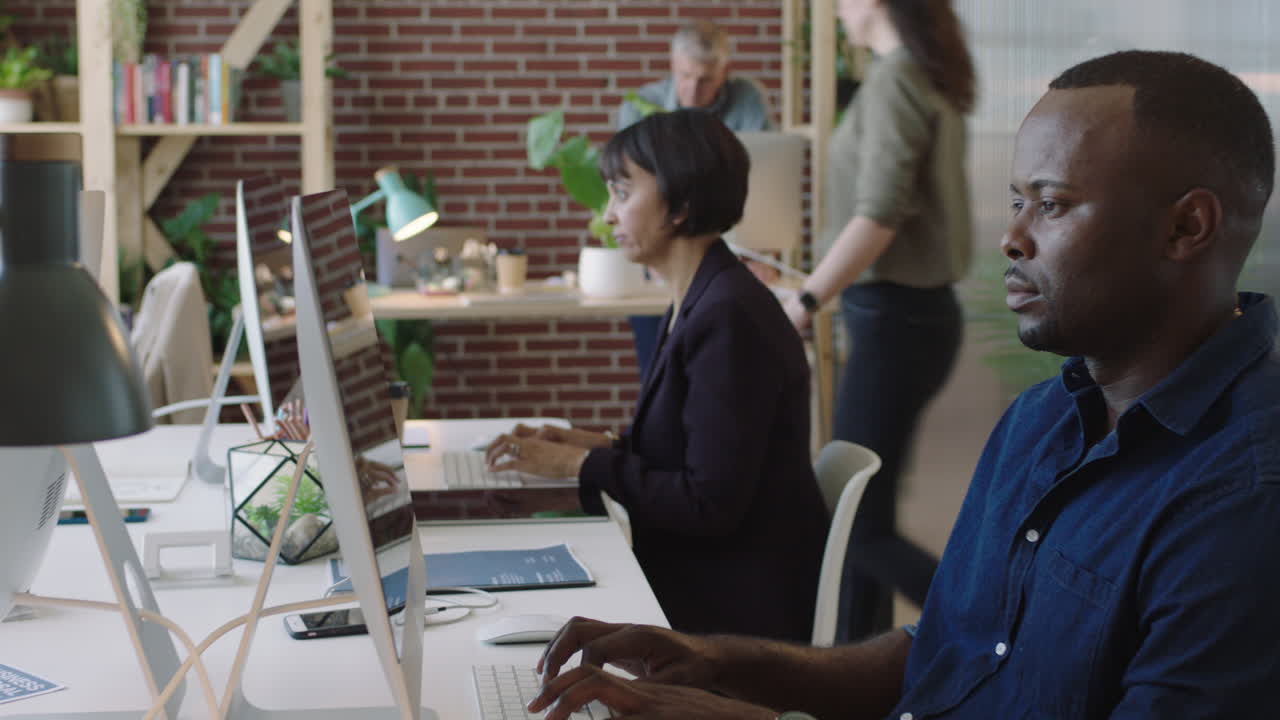 young african american businessman using computer working concentrating in creative multi ethnic office workspace colleagues busy background