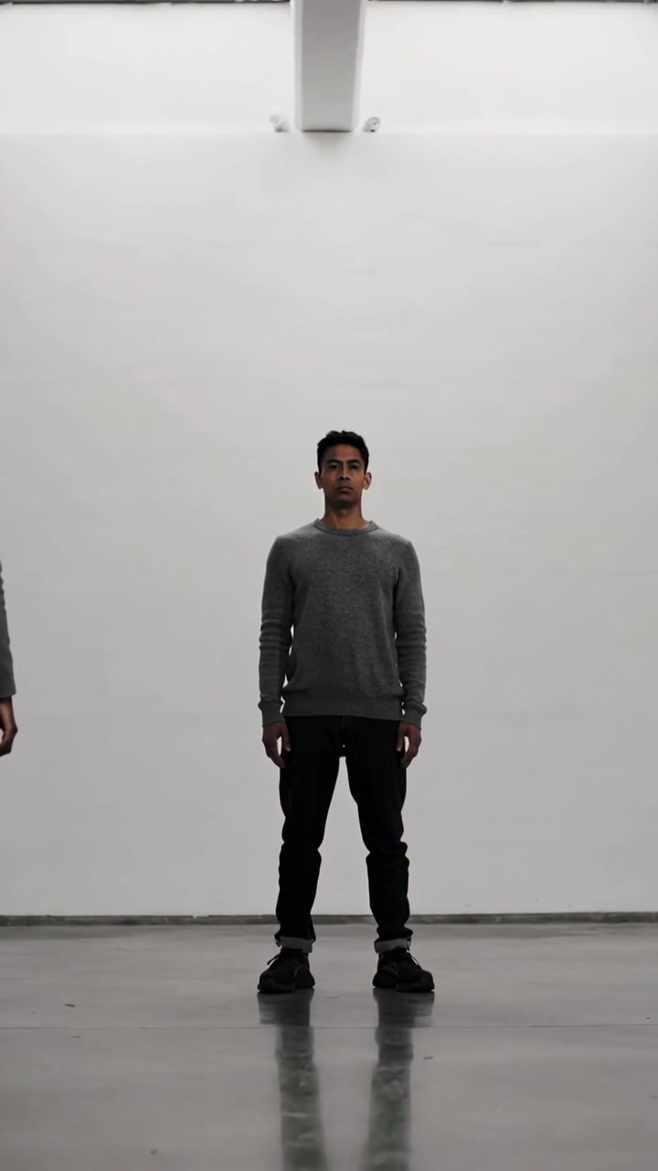 Vertical video: Standing man in gray sweater, pants as camera starting for gallery under skylight