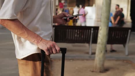 man with suitcase and smartphone on a city street