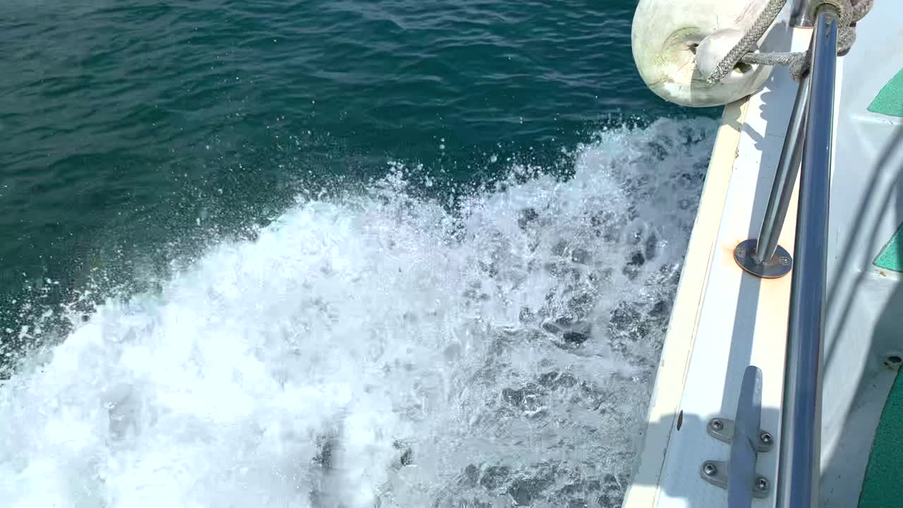 White foam coming out of the wake of the side of a motor boat at full speed sailing in the sea during the day close up shot