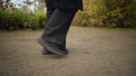 dynamic side view of a person's legs in black jeans and canvas shoes, capturing the essence of an autumnal stroll through a garden with vivid foliage and earthy tones