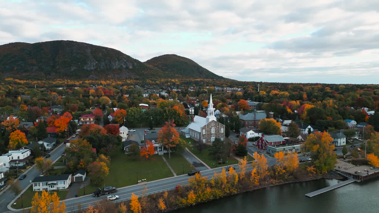 Aerial wide shot showing Mont Saint Hilaire area with Saint Hilaire church in the foreground and the Mont Saint Hilaire in the background during fall season, Quebec province, Canada