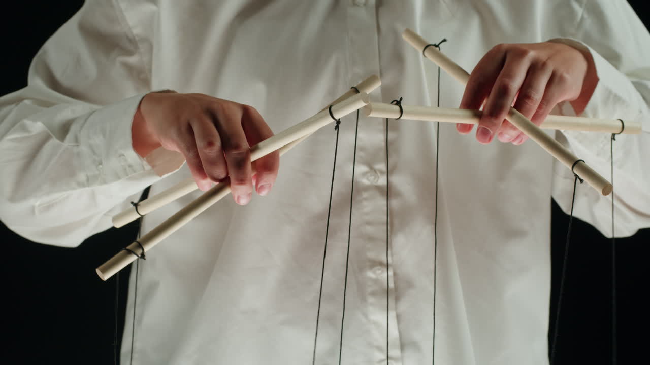 Person's Hands Manipulating Puppet Control Bars with Strings