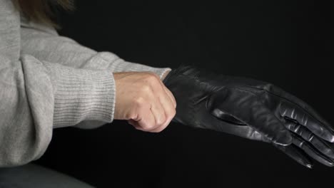 hands putting on black driving gloves medium shot on black background