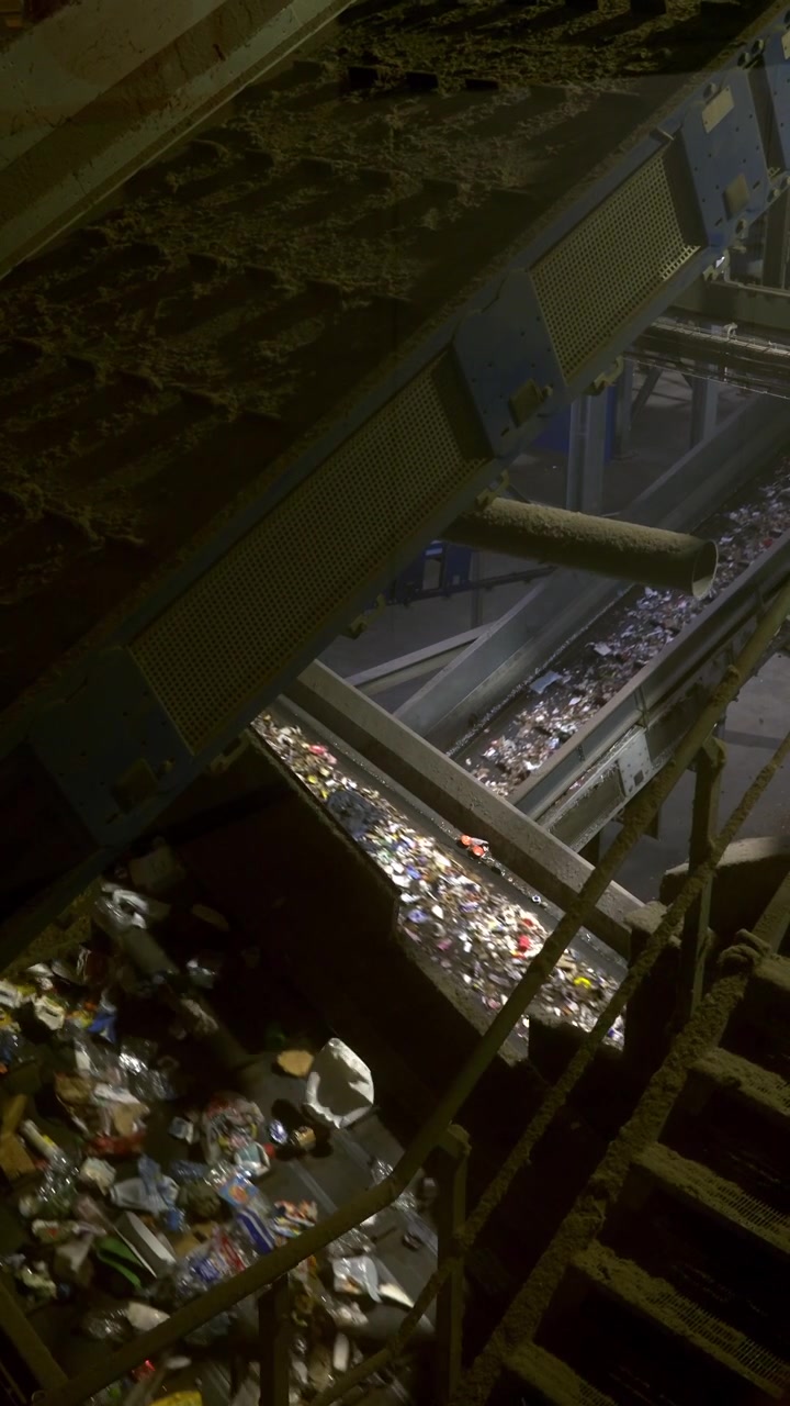Vue en plongée de déchets circulant sur des convoyeurs à l’intérieur d’un centre de tri et de recyclage en France.