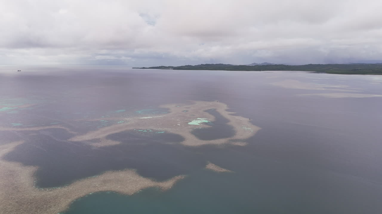 Aerial cinematic drone shot revealing coastal tropical waters and distant islands in Palau. Wide cinematic drone shot