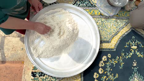 hacer masa de harina agregando agua a la harina en polvo para hacer fermentación y hornear pan plano en un horno de arcilla de vida rural para hacer pizza, galletas y pan en el pueblo, gente local en la terraza del balcón