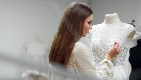 retrato de una chica creando un vestido de novia por pedido exclusivo cosiendo telas y piedras en un vestido vestido con un maniquí. producción de vestidos de novia. pequeño negocio
