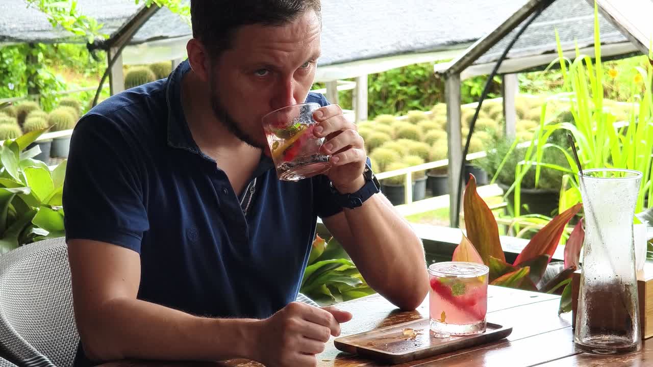 hombre disfrutando de una bebida refrescante en un café de jardín