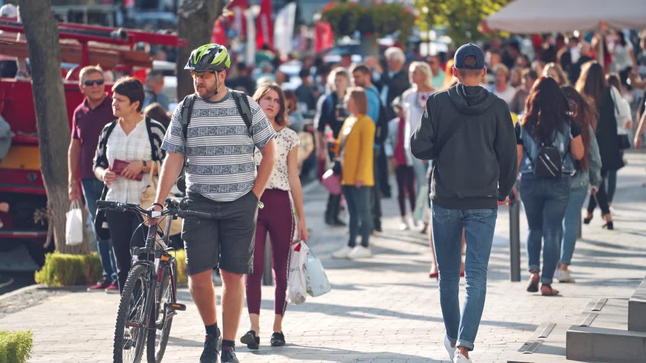 People moving in crowded city street. Crowd moving against background of urban landscape