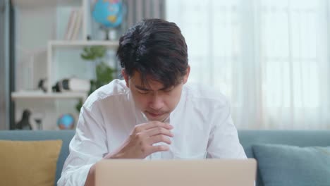 asian man being tired while using laptop computer in the living room
