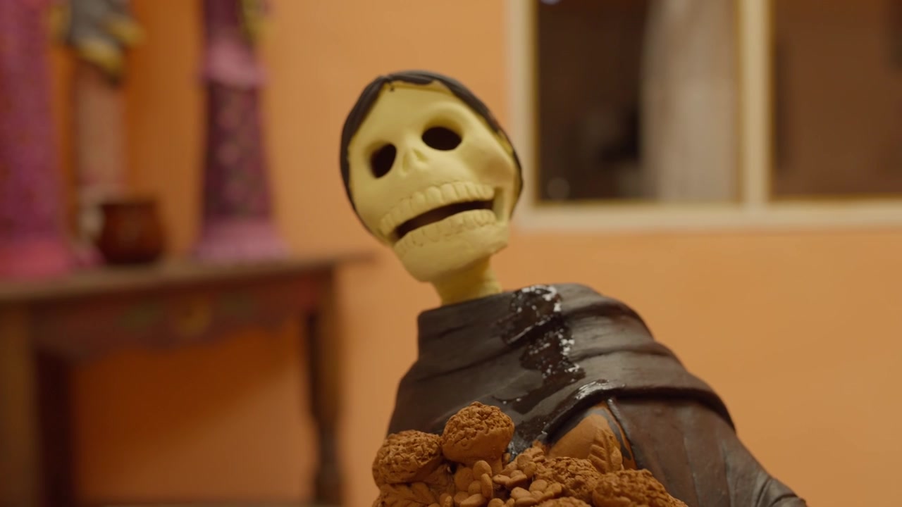 Artigiano che dipinge una scultura di Catrina fatta a mano con un pennello fine all'interno di un laboratorio, aggiungendo strati per scurire e creare la base dopo la cottura.