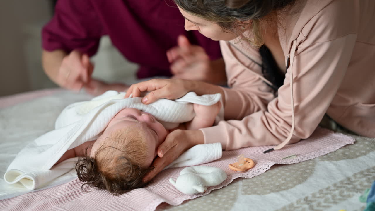 Madre che avvolge delicatamente un bambino in una morbida coperta durante una sessione di massaggio e cura