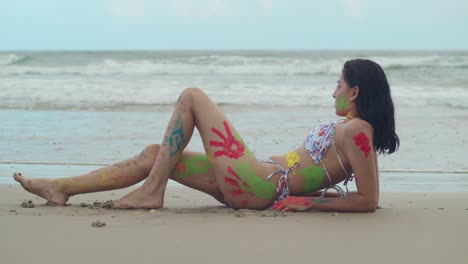 vibrant body paint adorned the bikini-clad figure of a young girl, creating a striking scene on a tropical beach in the caribbean with ocean waves in the background