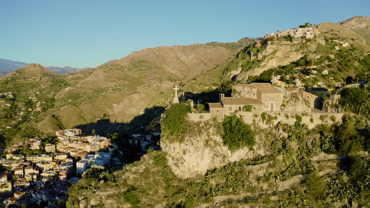 Kredsende droneoptagelse omkring kirke på kanten af en klippe. Frodige bjerge i siciliansk landskab