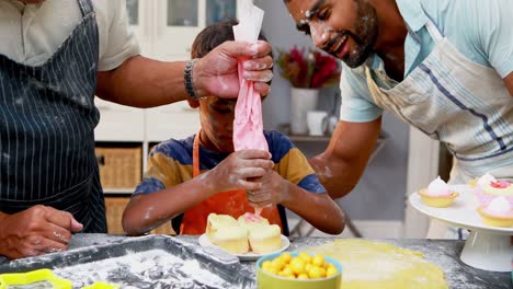 Grandfather-and-father-assisting-boy-to-make-cupcakes-4k