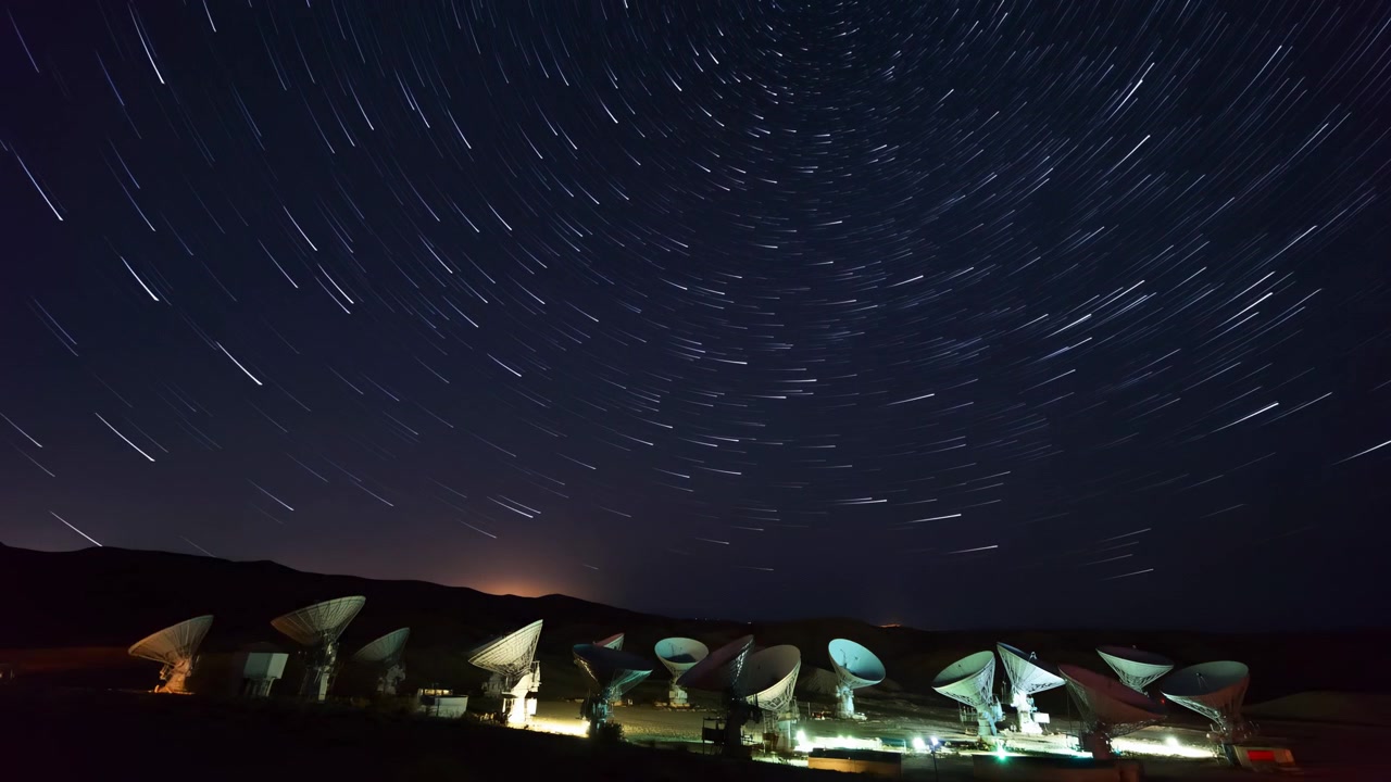 un cielo notturno tranquillo pieno di stelle e illuminato dalle luci della città, catturato in una vista panoramica grandangolare di un paesaggio urbano notturno. La scena presenta tonalità blu scuro e bianco