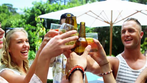 group of happy friends toasting beer bottles and glasses at outdoors barbecue party