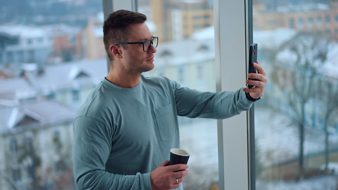 Man taking a selfie by the window with coffee