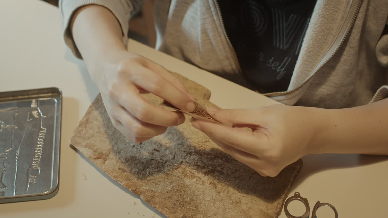 enrollar a mano un cigarrillo con tabaco, preparar papel y relleno en casa para fumar